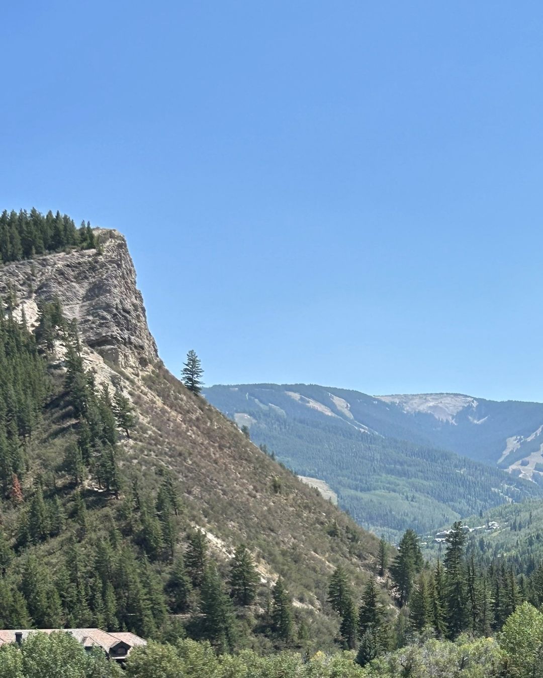 The cliff band above Avon with ski runs on the ridge across the valley on a clear summer day.