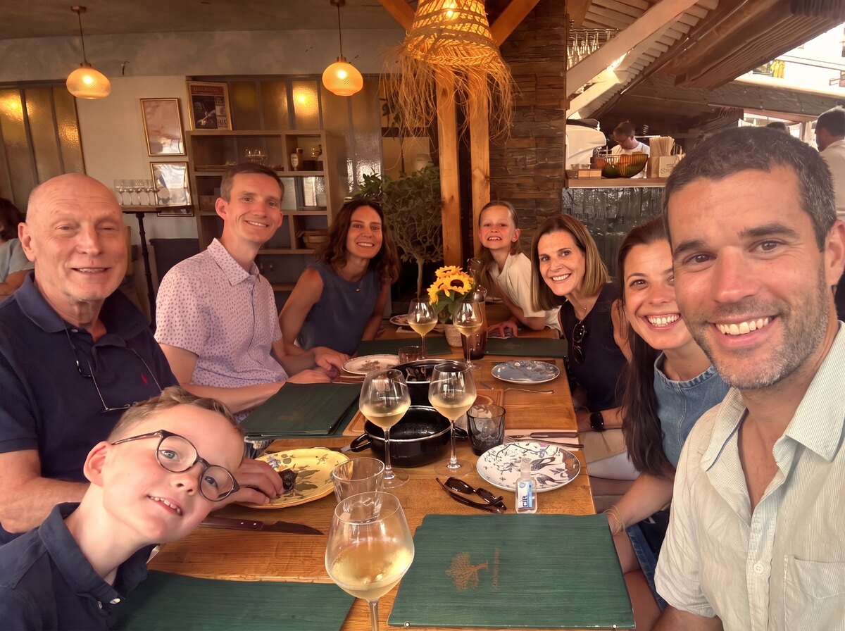Rick and Meg Sudekum seated with members of their family around a dinner table.